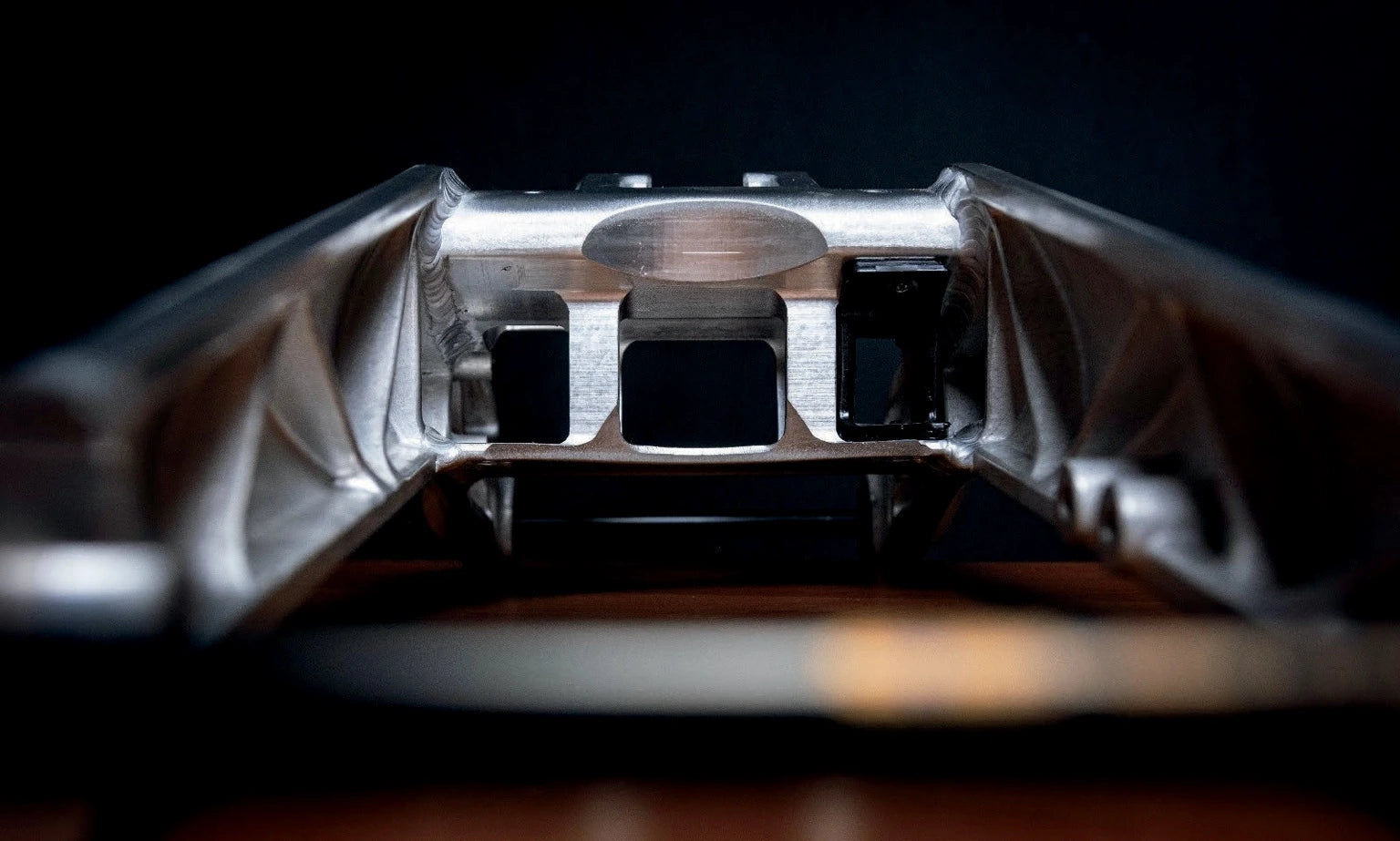 Close-up of IZI Brothers raw swingarm internal structure and weld details, studio lighting